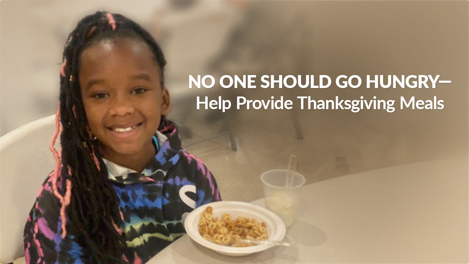 Girl sitting at a table with a plate of food.